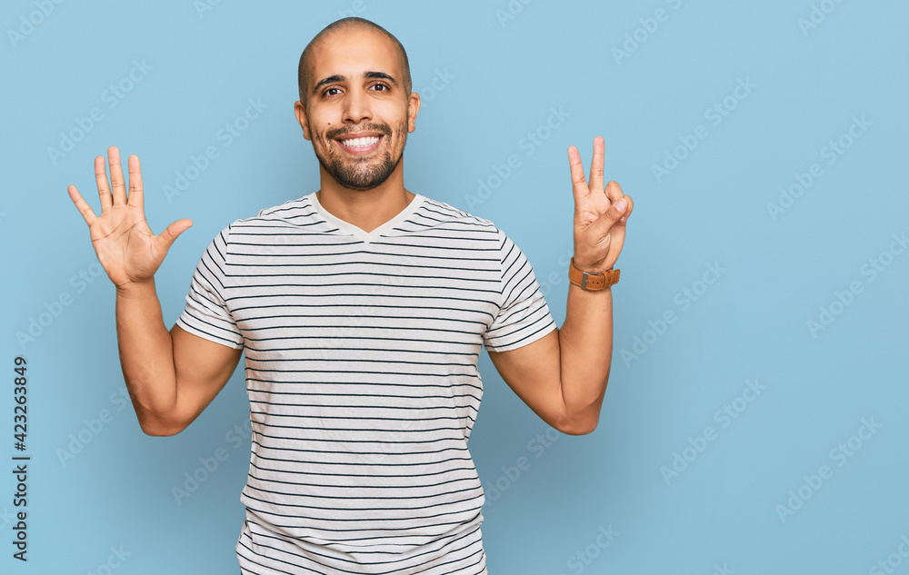 Naklejka premium Hispanic adult man wearing casual clothes showing and pointing up with fingers number seven while smiling confident and happy.