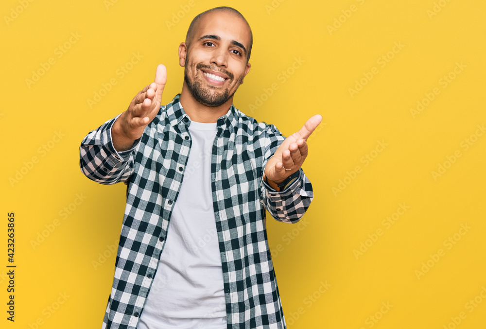 Naklejka premium Hispanic adult man wearing casual clothes looking at the camera smiling with open arms for hug. cheerful expression embracing happiness.