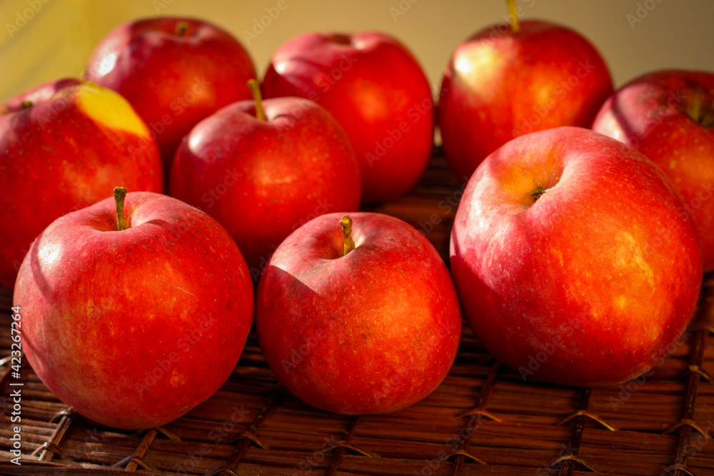 Several ripe red apples stand on a wicker basket illuminated by rays of the sun Several ripe red apples stand on a wicker basket illuminated by rays of the sun