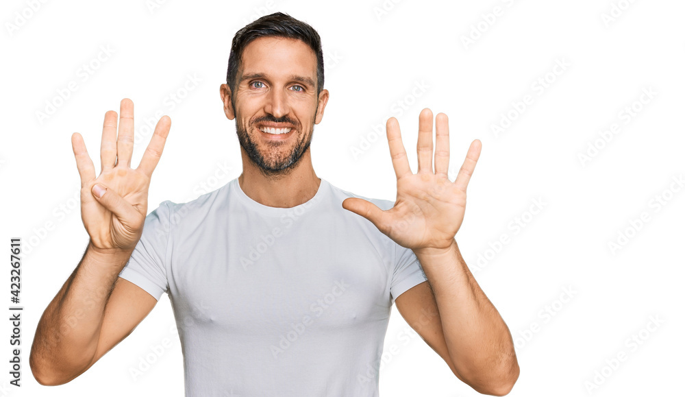 Handsome man with beard wearing casual white t shirt showing and pointing up with fingers number nine while smiling confident and happy. Handsome man with beard wearing casual white t shirt showing and pointing up with fingers number nine while smiling confident and happy.