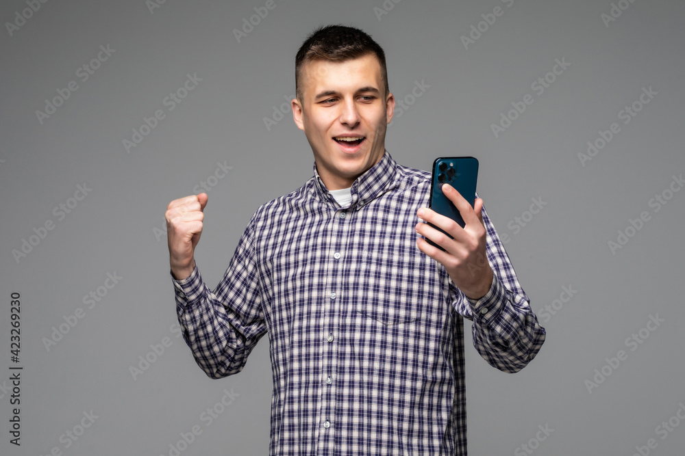 Excited Caucasian man look at smartphone happy get good text message isolated on grey studio background. Excited Caucasian man look at smartphone happy get good text message isolated on grey studio background.