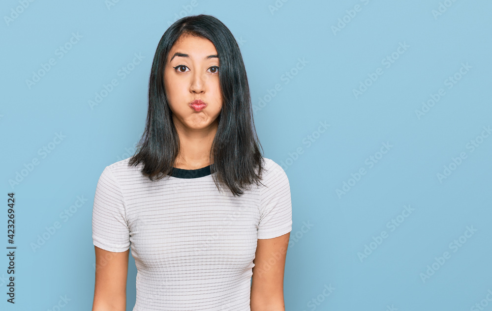 Beautiful asian young woman wearing casual white t shirt puffing cheeks with funny face. mouth inflated with air, crazy expression. Beautiful asian young woman wearing casual white t shirt puffing cheeks with funny face. mouth inflated with air, crazy expression.
