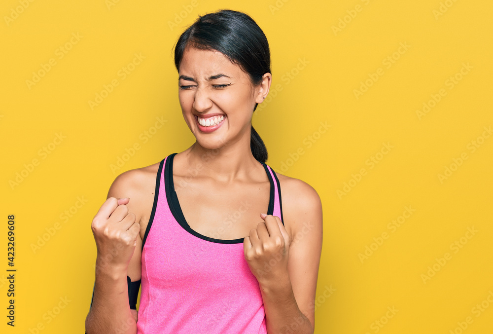 Beautiful asian young sport woman wearing sportswear and arm band very happy and excited doing winner gesture with arms raised, smiling and screaming for success. celebration concept. Beautiful asian young sport woman wearing sportswear and arm band very happy and excited doing winner gesture with arms raised, smiling and screaming for success. celebration concept.