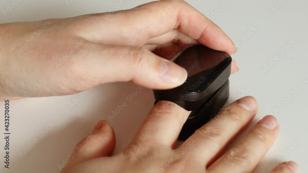 Close up of adult woman's hand wearing pulse oximeter to measure blood oxygen saturation Close up of adult woman's hand wearing pulse oximeter to measure blood oxygen saturation