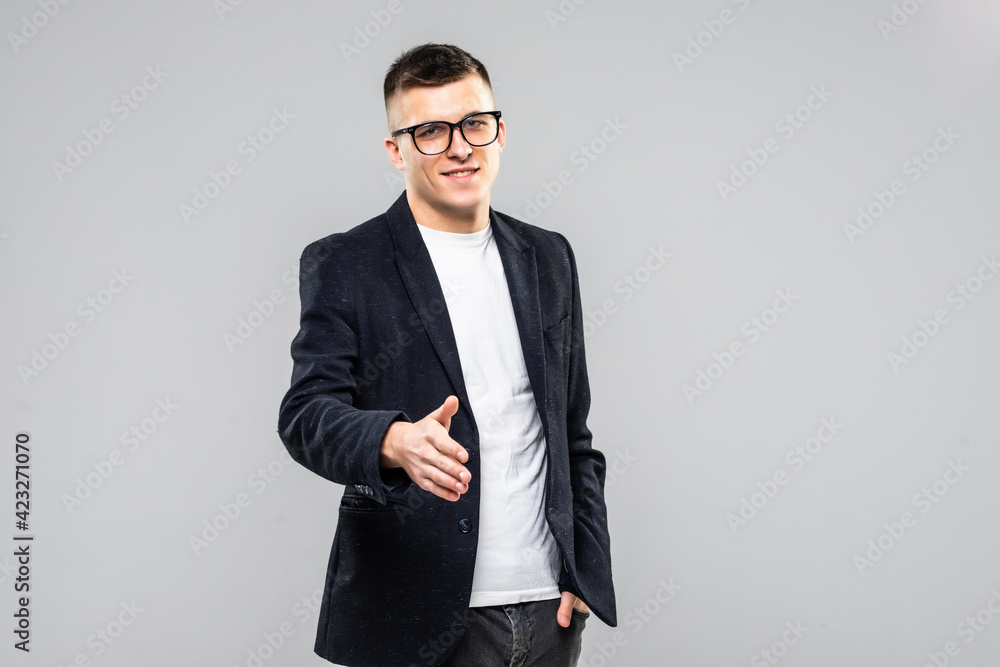 Portrait of businessman giving hand for handshake, with blank copyspace area for text or slogan, against grey background