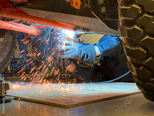 Welder welding on a offroad vehicle in a garage shop