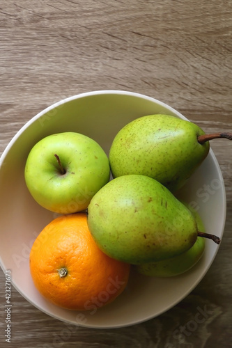 Bowl with pears, appples and oranges on a table. Flat lay.