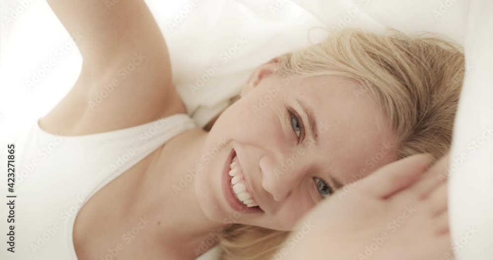 Woman Giving a Teasing Smile While Staying in Her Bedroom with White Sheets Woman Giving a Teasing Smile While Staying in Her Bedroom with White Sheets
