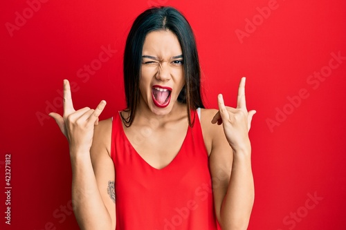 Young hispanic girl wearing casual style with sleeveless shirt shouting with crazy expression doing rock symbol with hands up. music star. heavy concept.