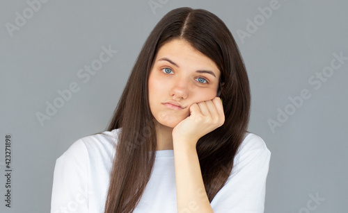 You waste my time on stupid talks. Bothered and bored cute female model leaning face on palm while standing over gray wall with indifferent annoyed expression