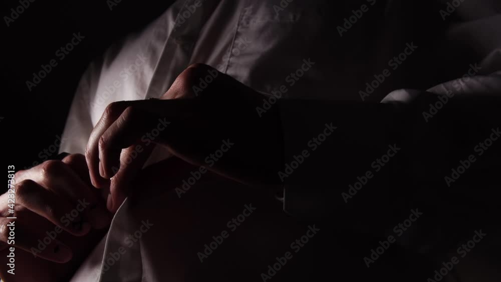 A man with rings and manicure is buttoning up a white shirt filmed in macro from below. Male person is wearing and preparing for the meeting. Groom is dressing for a wedding. Concept of formal clothes A man with rings and manicure is buttoning up a white shirt filmed in macro from below. Male person is wearing and preparing for the meeting. Groom is dressing for a wedding. Concept of formal clothes