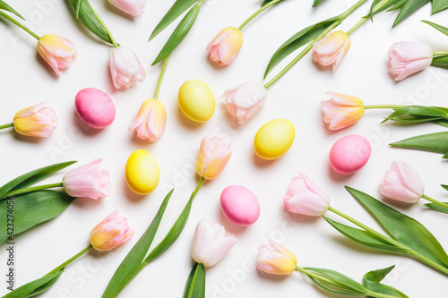 Easter layout of light pink and yellow spring flowers tulips and pastel colors eggs on a white background. Festive flat lay, happy easter concept. © magic_cinema