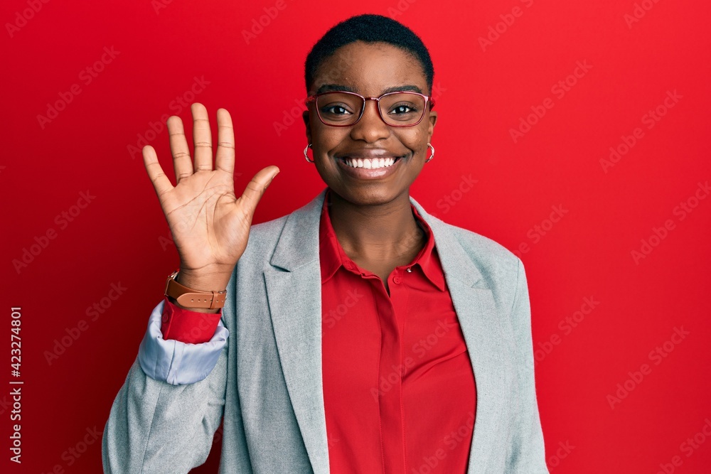 Naklejka premium Young african american woman wearing business jacket and glasses showing and pointing up with fingers number five while smiling confident and happy.