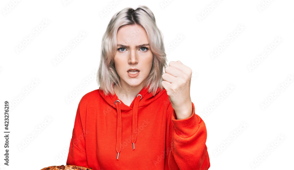 Young blonde girl holding italian pizza annoyed and frustrated shouting with anger, yelling crazy with anger and hand raised Young blonde girl holding italian pizza annoyed and frustrated shouting with anger, yelling crazy with anger and hand raised