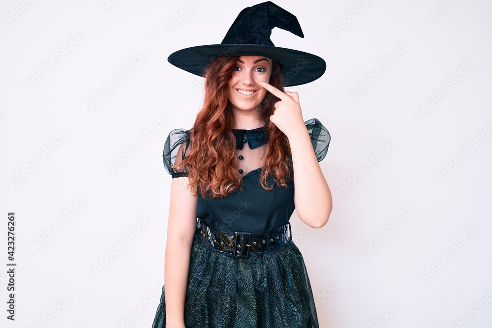 Young beautiful woman wearing witch halloween costume pointing with hand finger to face and nose, smiling cheerful. beauty concept Young beautiful woman wearing witch halloween costume pointing with hand finger to face and nose, smiling cheerful. beauty concept