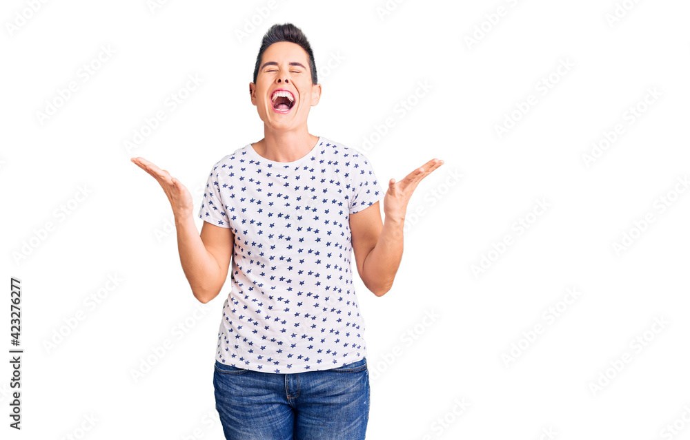 Young woman with short hair wearing casual clothes celebrating mad and crazy for success with arms raised and closed eyes screaming excited. winner concept Young woman with short hair wearing casual clothes celebrating mad and crazy for success with arms raised and closed eyes screaming excited. winner concept
