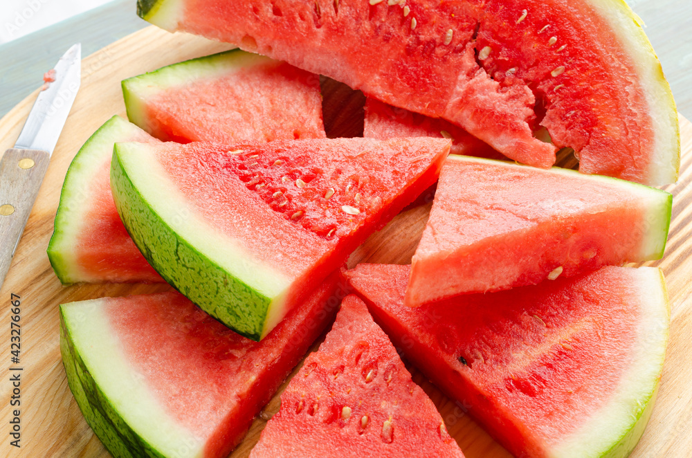 Slices of watermelon on a wood cutting board and wooden background Slices of watermelon on a wood cutting board and wooden background