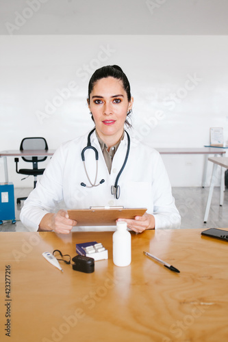 Portrait Of latin Female Doctor Wearing White Coat With Stethoscope In Hospital Office in Mexico city