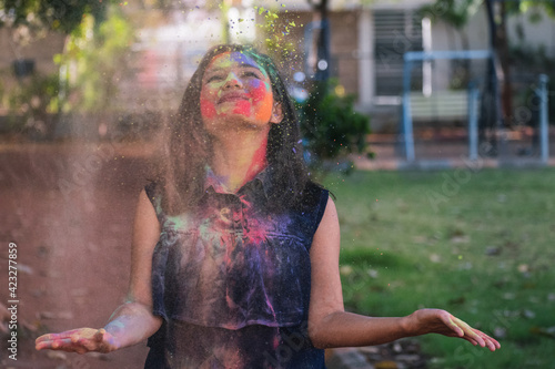 Portrait Of Indian girl Standing Being Covered In Coloured Powder At Holi Festival photo