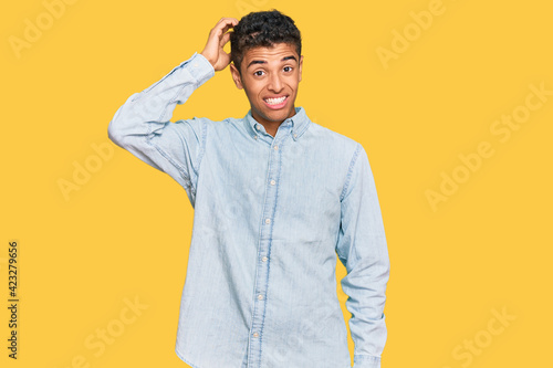 Young handsome african american man wearing casual clothes confuse and wonder about question. uncertain with doubt  thinking with hand on head. pensive concept.