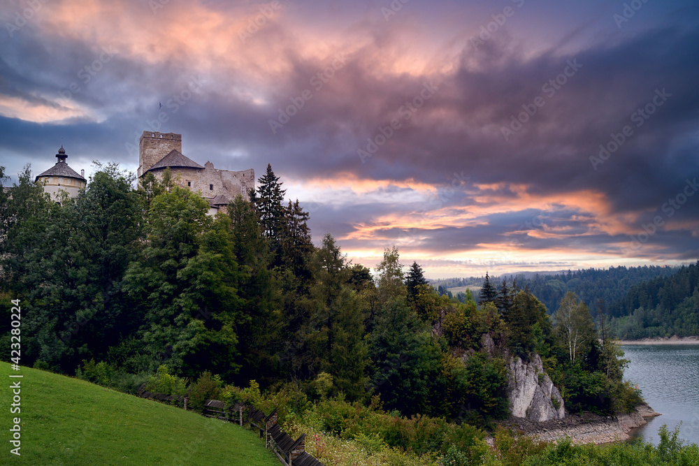 Medieval castle in Niedzica in Poland over the Czorsztyn Lake on the background of a picturesque cloudy sky during sunset.
