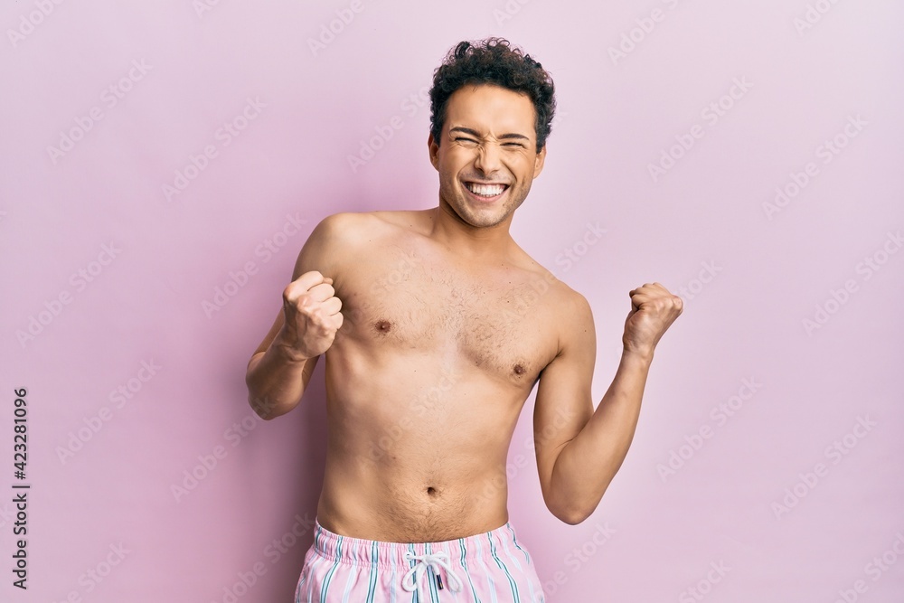 Fototapeta premium Young handsome man wearing swimwear shirtless excited for success with arms raised and eyes closed celebrating victory smiling. winner concept.