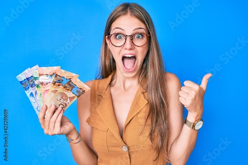 Foto Young blonde girl holding canadian dollars celebrating crazy and amazed for success with open eyes screaming excited
