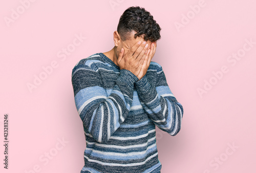 Hispanic young man wearing casual clothes with sad expression covering face with hands while crying. depression concept. © Krakenimages.com