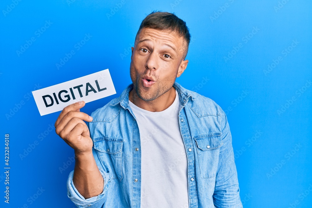 Handsome muscle man holding digital word on paper scared and amazed with open mouth for surprise, disbelief face Handsome muscle man holding digital word on paper scared and amazed with open mouth for surprise, disbelief face