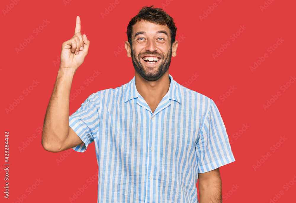 Handsome young man with beard wearing casual fresh shirt pointing finger up with successful idea. exited and happy. number one. Handsome young man with beard wearing casual fresh shirt pointing finger up with successful idea. exited and happy. number one.