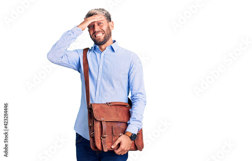 Young handsome blond man wearing elegant shirt holding briefcase stressed and frustrated with hand on head, surprised and angry face © Krakenimages.com