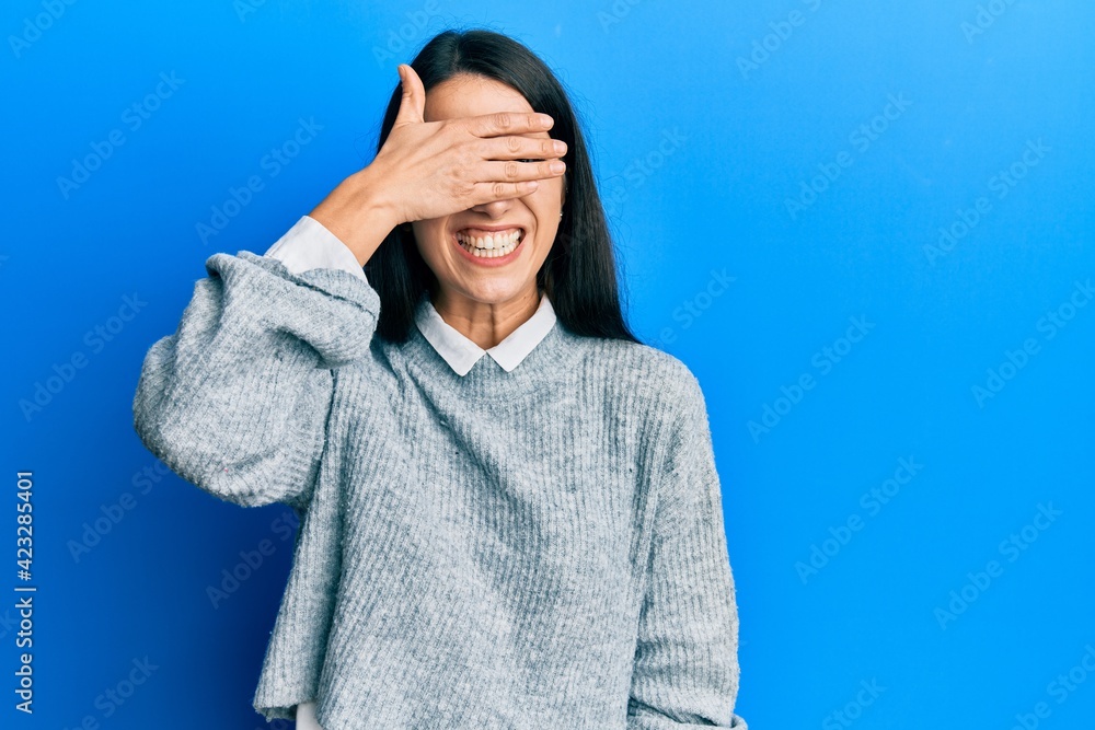 Young hispanic woman wearing casual clothes smiling and laughing with hand on face covering eyes for surprise. blind concept. Young hispanic woman wearing casual clothes smiling and laughing with hand on face covering eyes for surprise. blind concept.