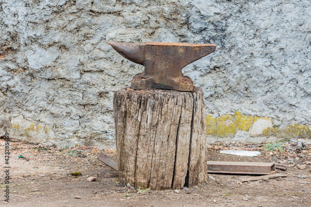 The blacksmith's old anvil. The anvil stands on a vertical log. The blacksmith's old anvil. The anvil stands on a vertical log.
