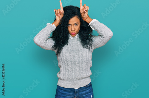 Middle age african american woman wearing casual clothes doing funny gesture with finger over head as bull horns