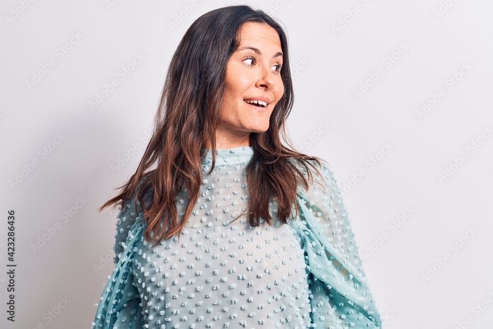 Young beautiful brunette woman wearing casual t-shirt standing over isolated white background looking to side, relax profile pose with natural face and confident smile.