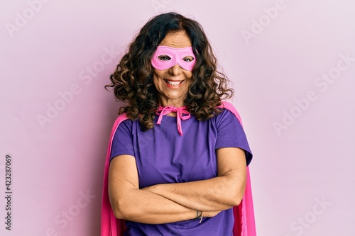 Middle age hispanic woman wearing super hero costume happy face smiling with crossed arms looking at the camera. positive person.