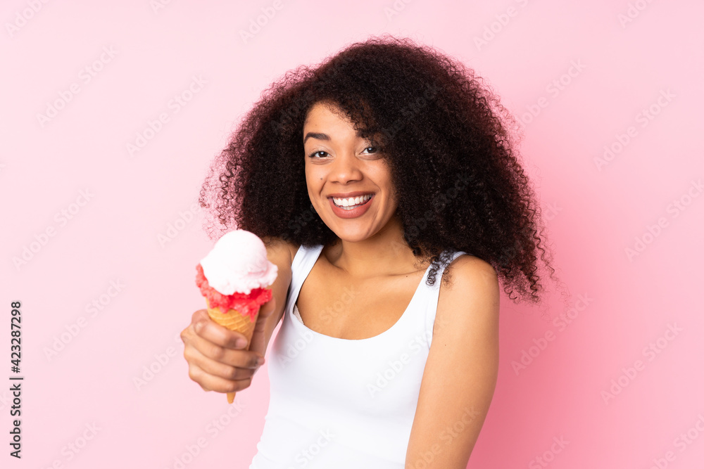 Young african american woman holding a cornet ice cream isolated on pink background Young african american woman holding a cornet ice cream isolated on pink background