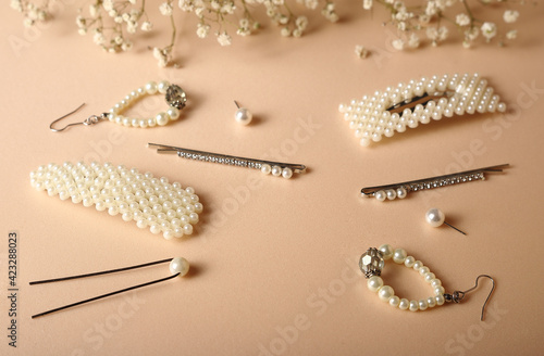 pearl jewelry earrings and hairpins on beige background