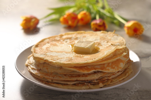 pancakes on a white plate with butter on a background of yellow flowers