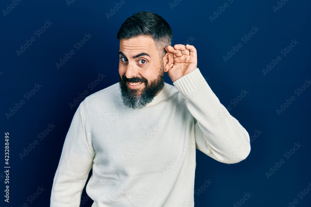 Fototapeta premium Young hispanic man wearing casual clothes smiling with hand over ear listening an hearing to rumor or gossip. deafness concept.