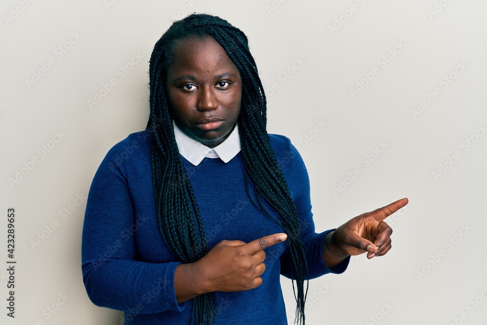 Young black woman with braids pointing up with fingers to the side depressed and worry for distress, crying angry and afraid. sad expression. Young black woman with braids pointing up with fingers to the side depressed and worry for distress, crying angry and afraid. sad expression.