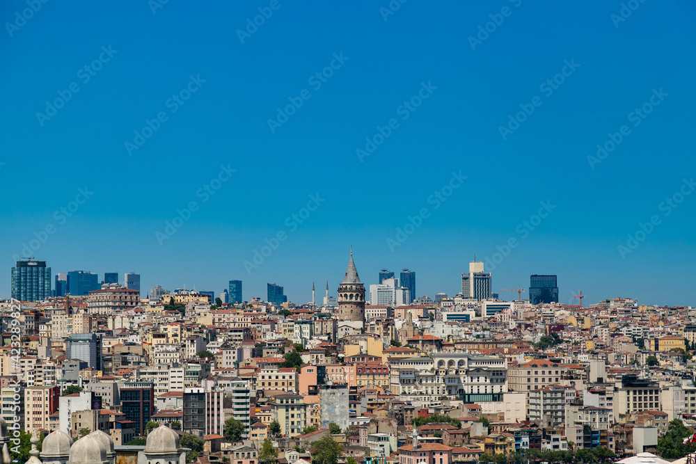 Beautiful panoramic view of cityscape of Istanbul with a lot of colorful buildings and rooftops including Galata Tower with clear blue sky. Summer urban background with copy space area for your text
