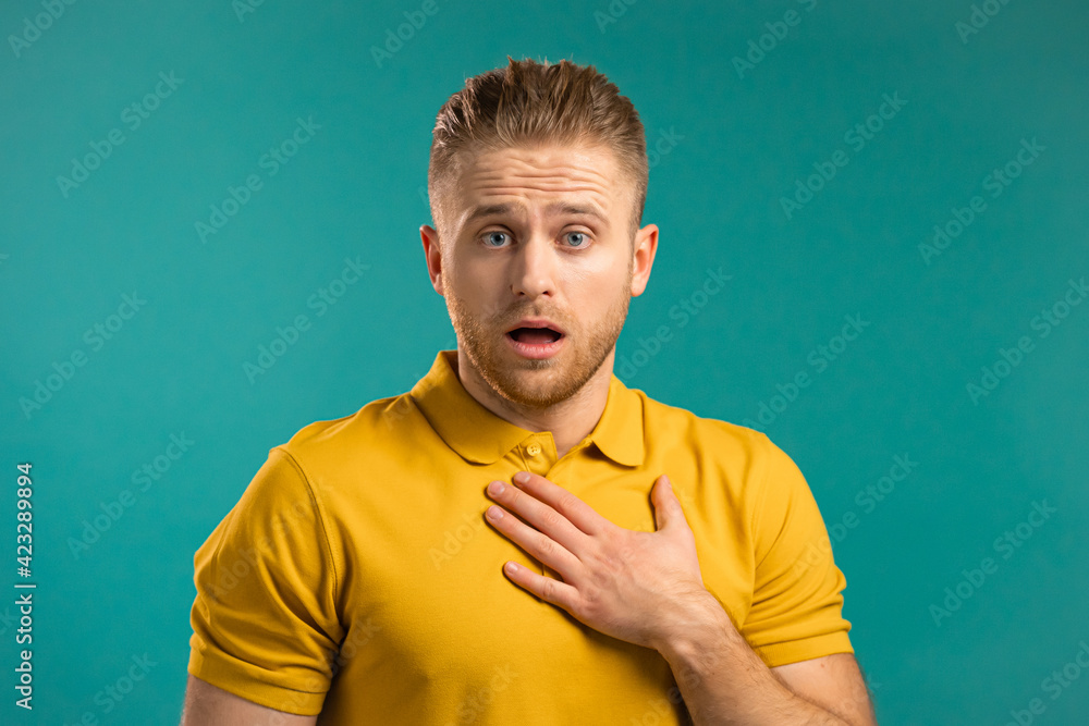 Frightened european man afraid of something and looks into camera with big eyes full of horror over blue wall background. Frightened european man afraid of something and looks into camera with big eyes full of horror over blue wall background.