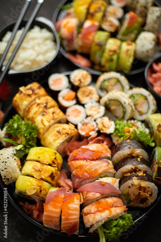 Assorted sushi set served on dark dark background. Top view of seafood, various maki rolls