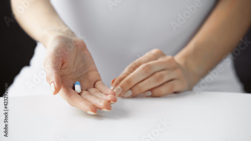 cropped view of pregnant woman holding pill, blurred background