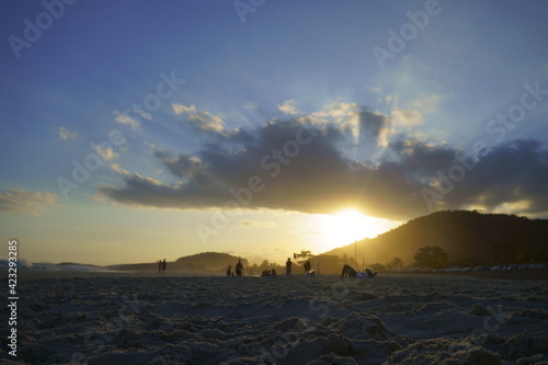 beautiful sunset at Piratininga beach, Niterói, overlooking the hills of Rio de Janeiro. Silhouette of some people on the beach. Sunny summer day.