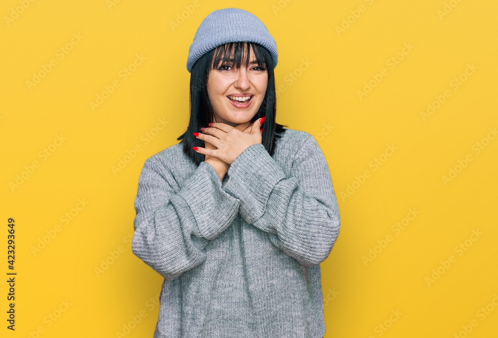 Young hispanic woman wearing cute wool cap shouting and suffocate because painful strangle. health problem. asphyxiate and suicide concept. Young hispanic woman wearing cute wool cap shouting and suffocate because painful strangle. health problem. asphyxiate and suicide concept.