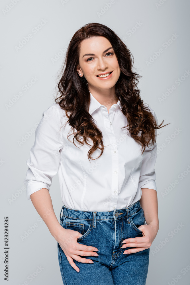 Smiling brunette woman looking at camera isolated on grey Smiling brunette woman looking at camera isolated on grey