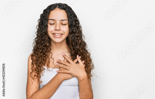Teenager hispanic girl wearing casual clothes smiling with hands on chest with closed eyes and grateful gesture on face. health concept.