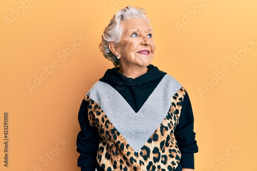 Senior grey-haired woman wearing sportswear looking to side, relax profile pose with natural face and confident smile.